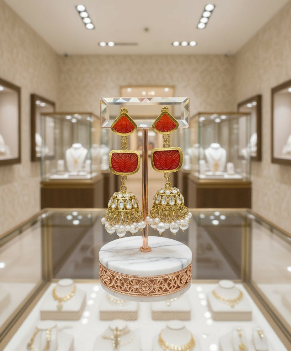 A pair of gold-plated sugar stone drop jhumka earrings with pink stones and white pearl-like accents.