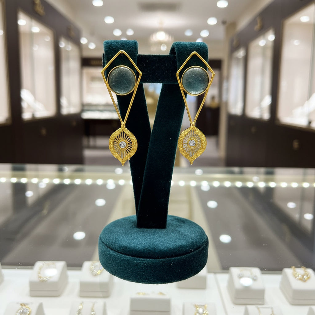 A pair of gold-colored filigree earrings featuring round yellow stones at the center, presented against a white background.