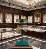 A pair of gold-coloured filigree earrings featuring round yellow stones at the centre, presented against a white background.