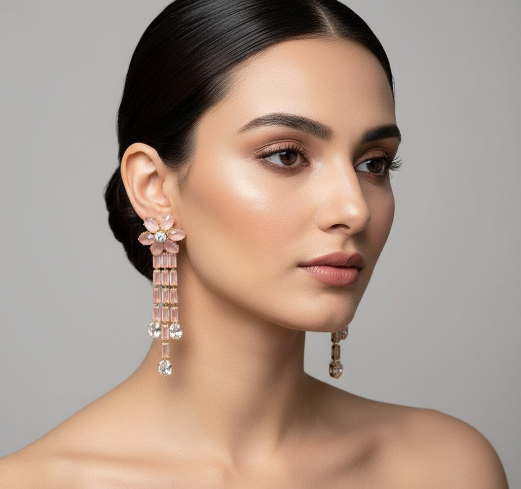 A pair of silver finish cubic zirconia flower drop earrings displayed on a stand, featuring a series of connected stones and flowers.