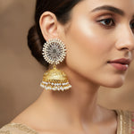 A pair of gold-plated brass jhumka earrings with intricate circle studs, nano pearl accents, and ornate deer detailing.