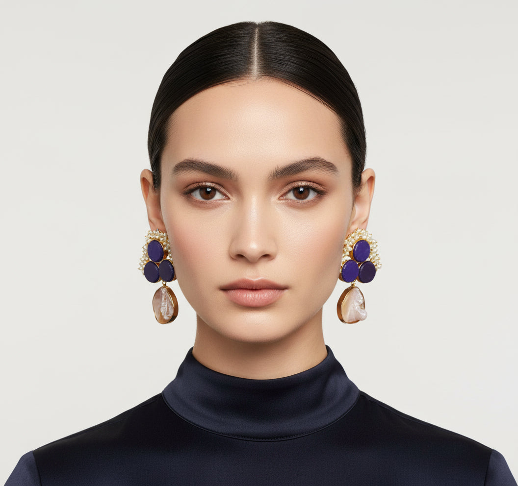 A pair of blue sugar stone stud earrings with gold-colored accents, displayed on a black stand.