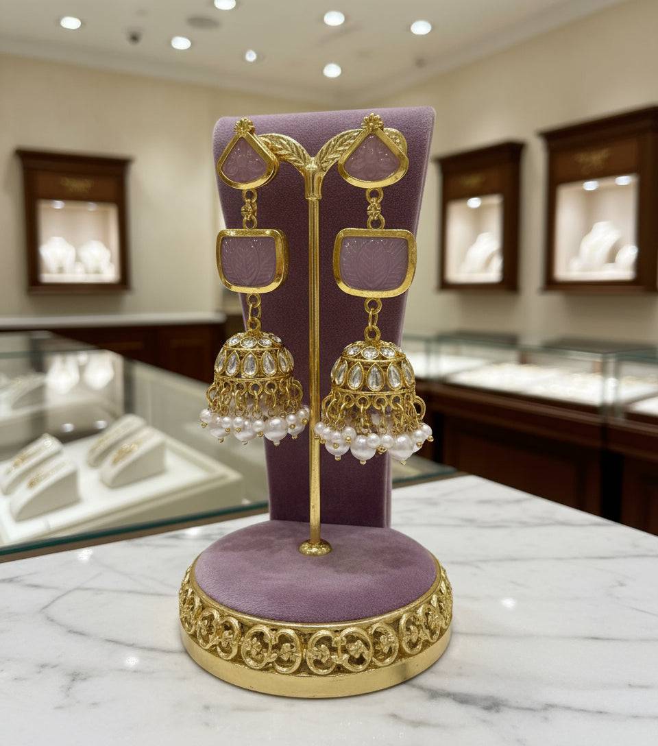 A pair of gold-plated sugar stone drop jhumka earrings with pink stones and white pearl-like accents.