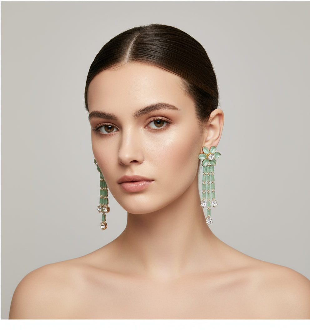A pair of silver finish cubic zirconia flower drop earrings displayed on a stand, featuring a series of connected stones and flowers.