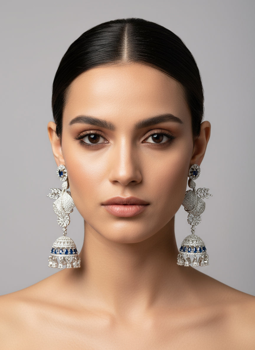 A pair of silver finish American diamond drop Jhumka earrings displayed on a stand.