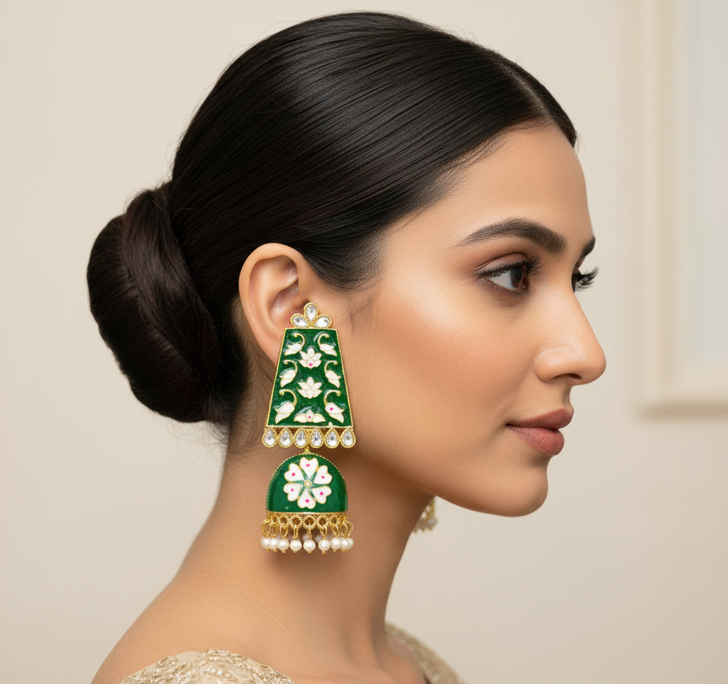 A pair of gold-plated Meenakari long Jhumka earrings with green and white enamel work and pearl accents.
