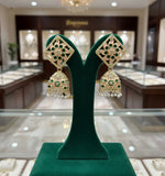 A pair of gold-plated brass Meenakari stud Jhumka earrings with green and white stones.
