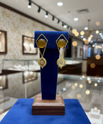 A pair of gold-coloured filigree earrings featuring round yellow stones at the centre, presented against a white background.