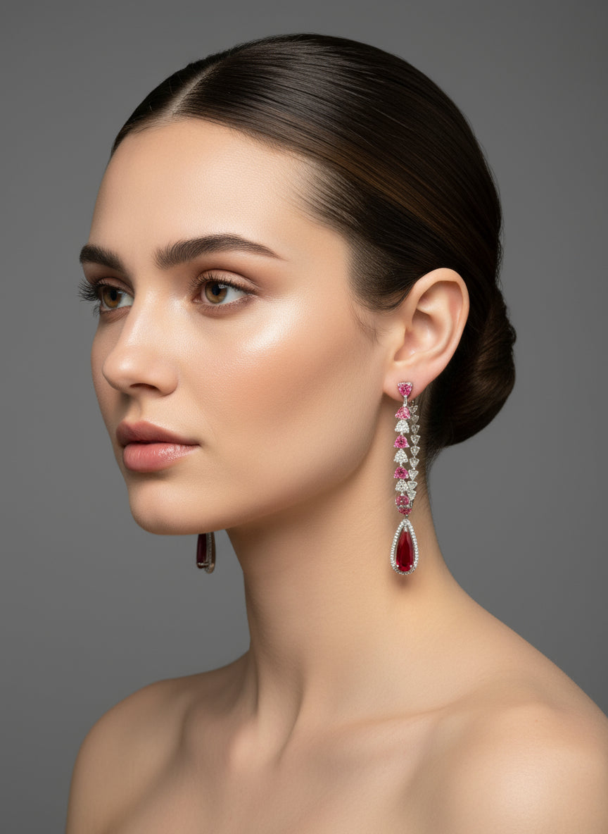 A pair of silver finish American diamond Jhumka bali earrings with green and clear stones on a stand.