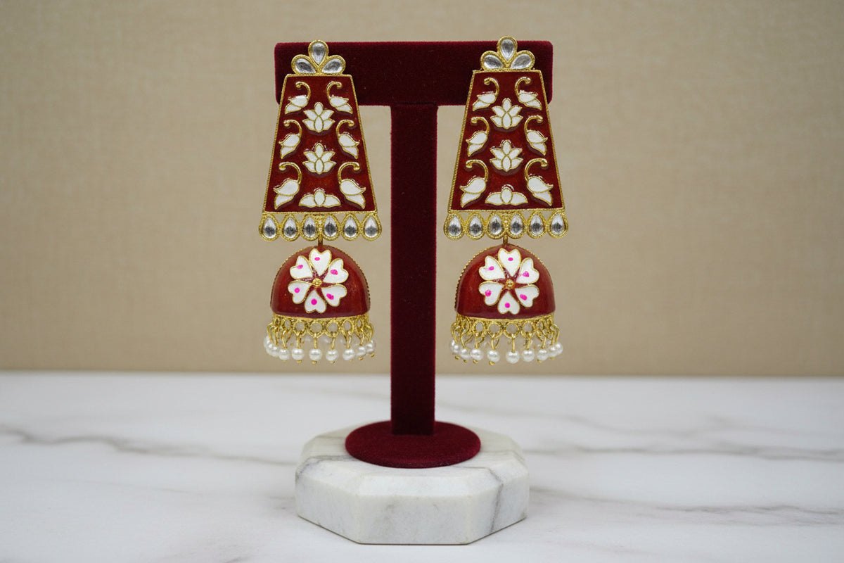 A pair of gold-plated Meenakari long Jhumka earrings with green and white enamel work and pearl accents.