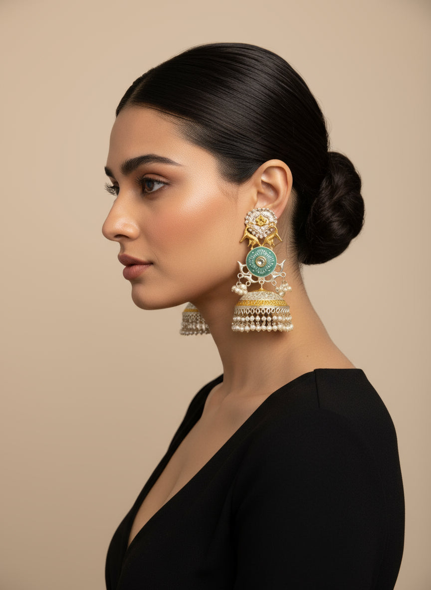 A pair of silver long Jhumkas with intricate designs and small pearls hanging from the bottom.