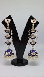 A pair of silver-plated tulip-shaped long jhumka earrings with multicolor details, displayed on a black stand.
