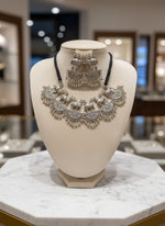 Silver jewellery set on a black stand with a blurred background