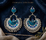 A pair of ornate silver-toned crescent-shaped earrings with turquoise blue enamel details, displayed on a dark navy velvet fabric background. The brand name 'FAMAZA COUTURE' is printed at the top.