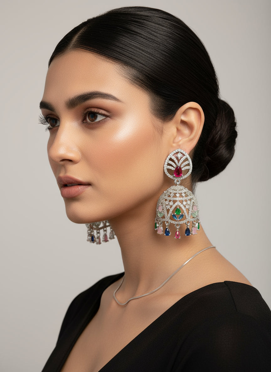 A pair of silver finish American diamond multi-colored Jhumka earrings displayed on a stand.