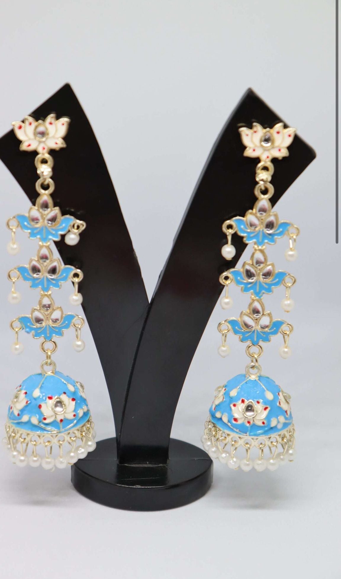 A pair of silver-plated tulip-shaped long jhumka earrings with multicolor details, displayed on a black stand.