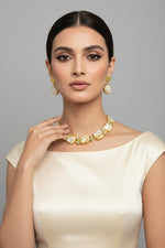 A Baroque pearl choker necklace with square-shaped mother of pearls and kundan accents, paired with matching earrings, against a black background.