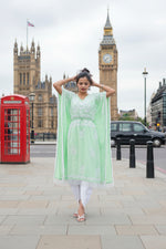 A girl is posing in an apple green chikankari kaftan by famaza couture