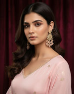 A beautiful model showcasing posh rose gold AD stone earrings in a luxury studio setting, styled with a light pink desi dress for a premium bridal jewellery look.