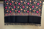 A black colour pashmina scarf with Kashmiri embroidery in a floral pattern, featuring tassels on the ends.
