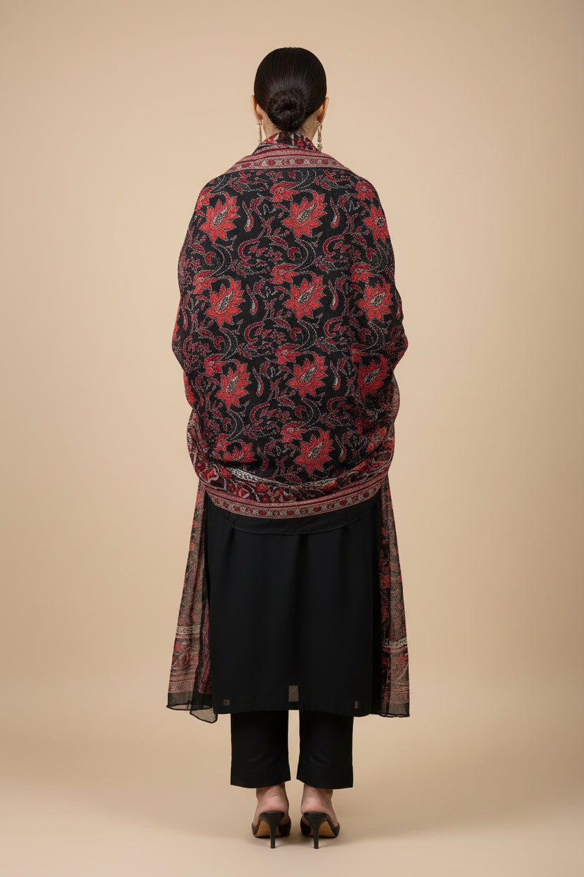 A black long rear view of this kurta with red and pink floral embroidery on the sleeves cuff and a red printed dupatta is, displayed on a hanger in a Famaza Couture store.