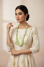 A black mannequin showcasing a Bollywood style lime green colour Mona Lisa stone and lime green colour nano crystal beaded Mala set, with white colours of baroque pearls and gold-tone accents.