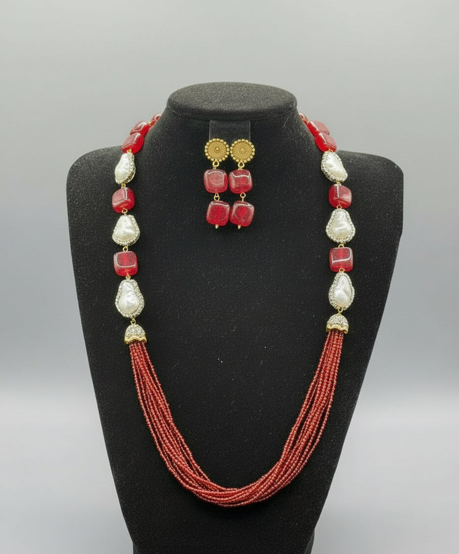 A black mannequin showcasing a Bollywood style maroon Mona Lisa stone and maroon nano crystal beaded Mala set, with white baroque beads and gold-tone accents.