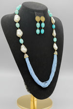 A black mannequin showcasing a Bollywood style sky blue colour Mona Lisa stone and blue colour nano crystal beaded Mala set, with white colours of baroque pearls and gold-tone accents.
