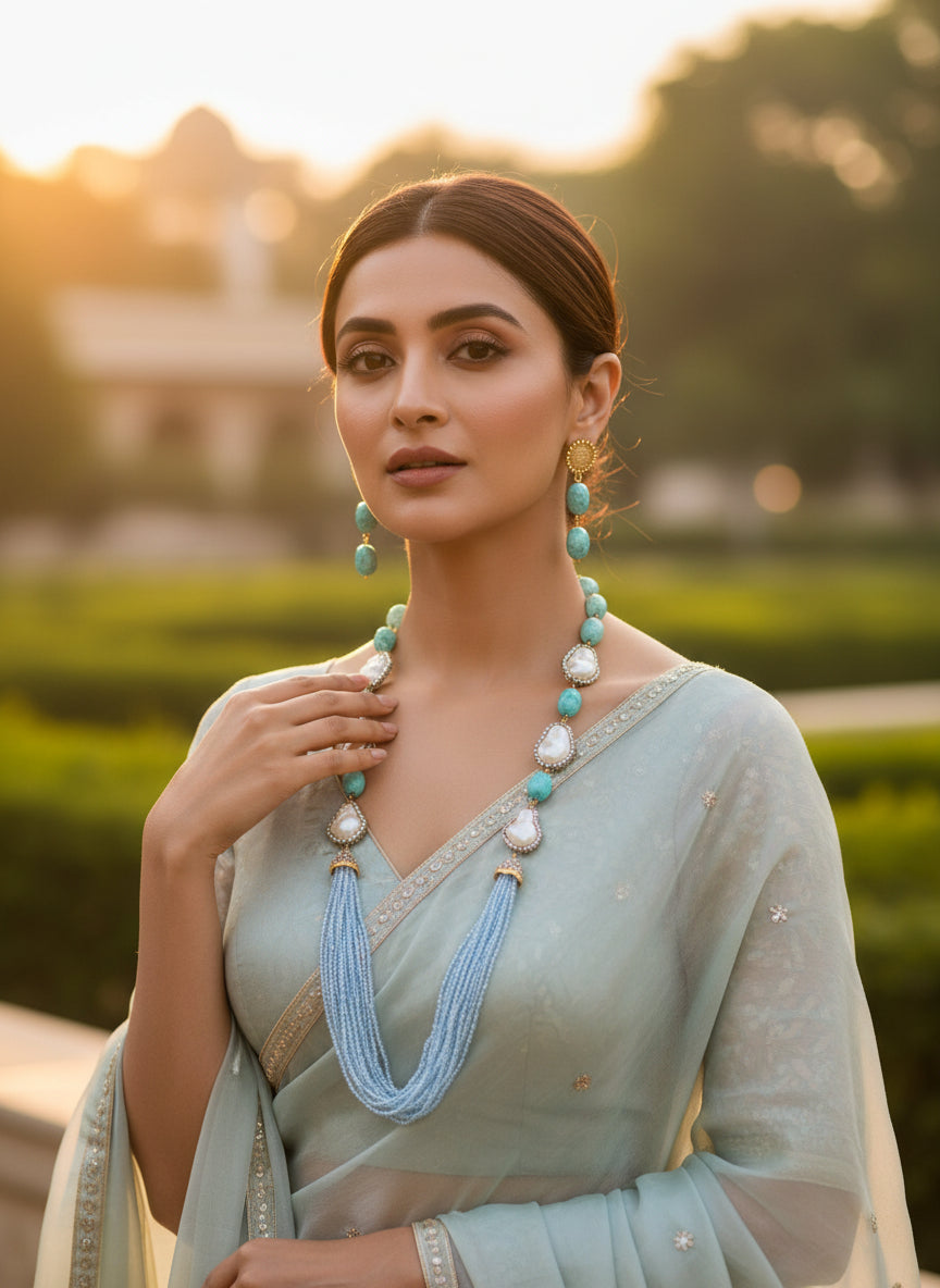 A black mannequin showcasing a Bollywood style sky blue colour Mona Lisa stone and blue colour nano crystal beaded Mala set, with white colours of baroque pearls and gold-tone accents. Party wear jewellery set.