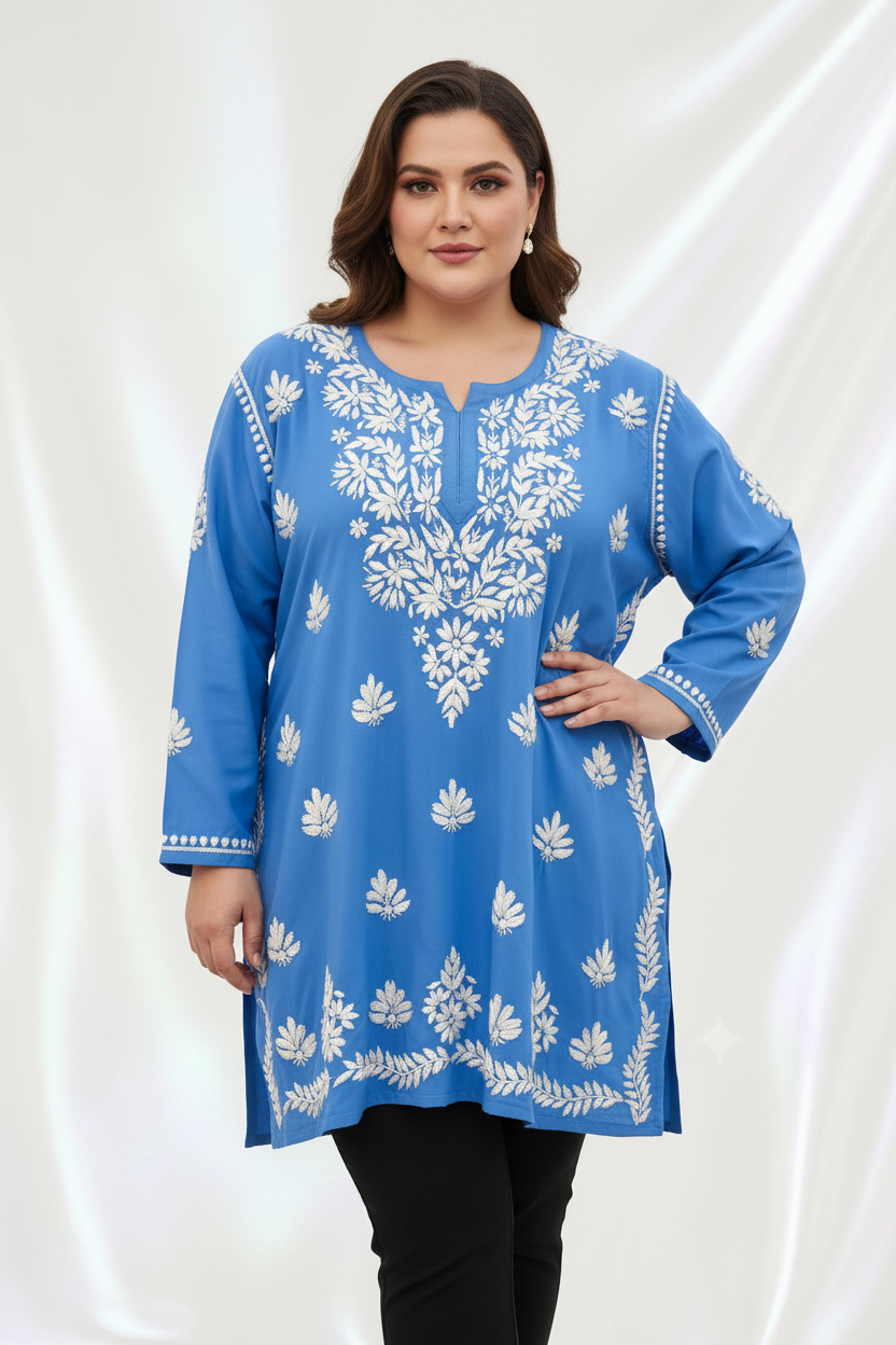 A woman modeling a blue long-sleeve kurta with white floral embroidery, paired with black pants, against a draped white fabric background.