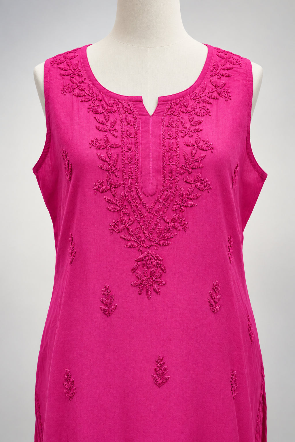 A bright magenta pink sleeveless kurta with floral embroidery on the chest and scattered embroidered motifs across the fabric, hanging on a white hanger.