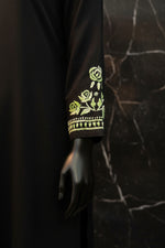 A close-up of a black sleeve featuring detailed green and white floral embroidery with rose motifs and a decorative border.