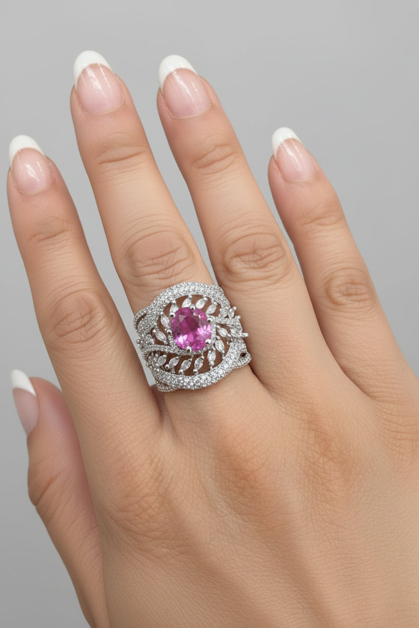 A close-up of a posh lady hand is wearing a silver-toned leaf-shaped ring with a prominent oval pink gemstone and small clear stones.