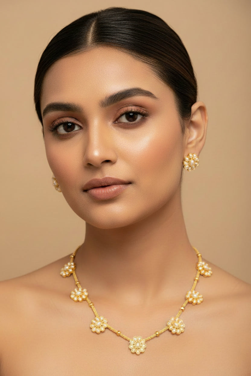 A dainty gold-toned necklace with five sunburst-style pearl flowers and matching sunburst stud earrings.
