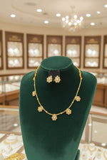 A delicate gold-toned jewelry set showcasing the spacing of the pearl floral charms and the coordinating uniquely shaped studs.