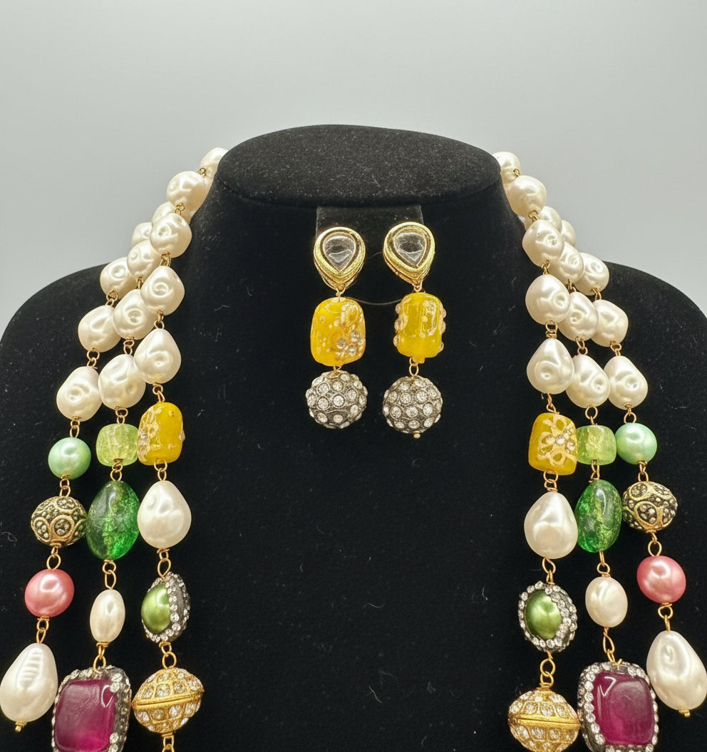 A gold-plated Kundan-studded and pearl-beaded handcrafted jewellery set, consisting of a necklace and earrings, displayed against a black background. Party wear set.