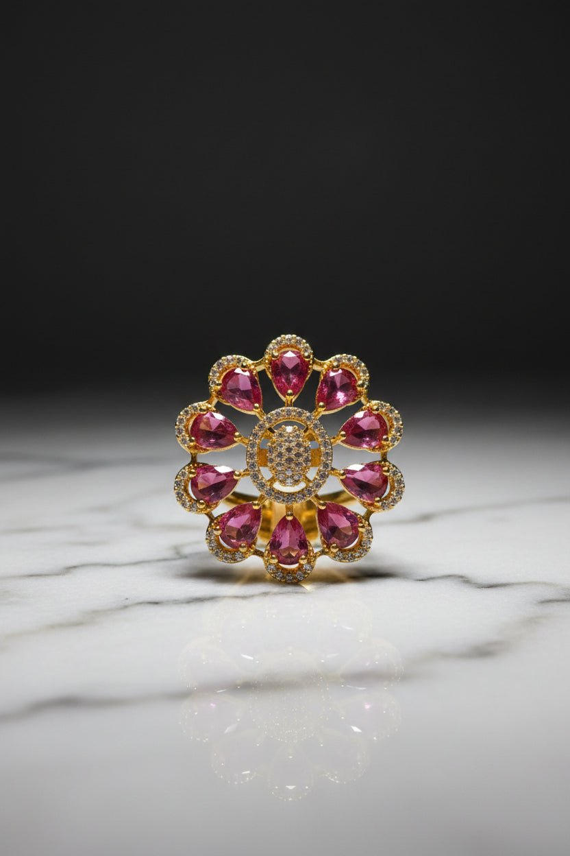 A gold flower-shaped brooch with pink teardrop gemstones and a central cluster of clear stones, held by a hand against a white furry background.