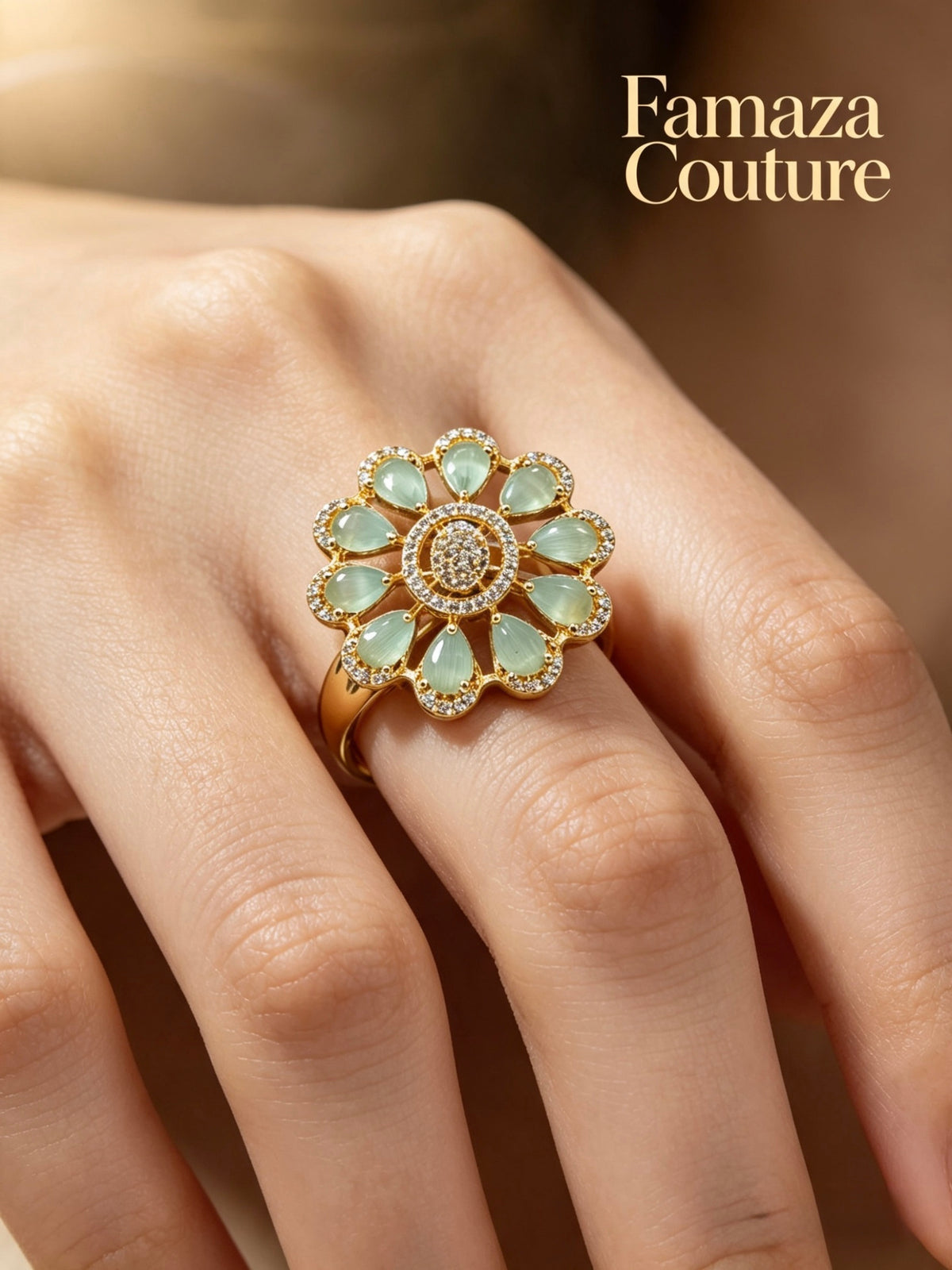 A gold flower-shaped ring with light green marquise-cut stones and a central round stone cluster, worn on a hand. The brand name 'Famaza Couture' is printed in gold text in the top right corner.