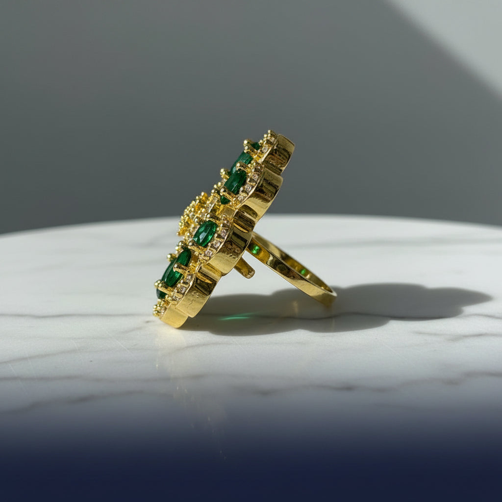 A gold ring with green gemstone accents, photographed on a textured gray faux fur surface.