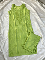 A light green sleeveless kurta with matching embroidered pants, laid flat on a white satin fabric background.