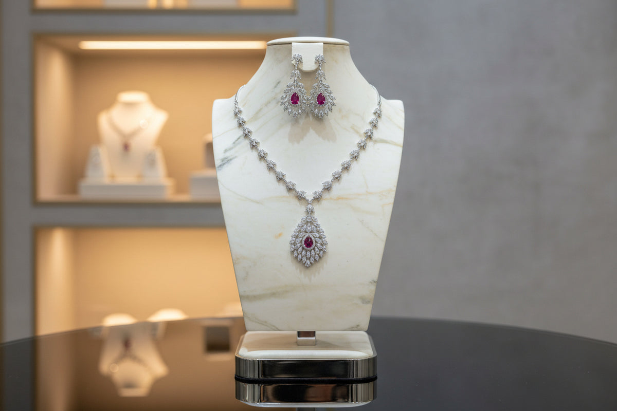 A mannequin showcasing a necklace and earrings set with leaf designs, featuring American diamonds and hot pink semi-precious stones. Party wear set.