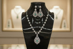 A mannequin showcasing a necklace and earrings set with leaf designs, featuring American diamonds and turquoise semi-precious stones.