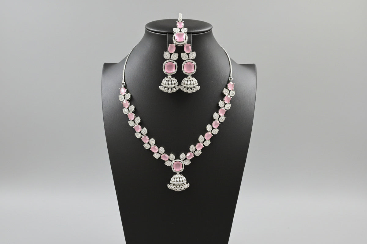 A mannequin showcasing a silver plated necklace set with pink and white stones, accompanied by earrings and a maang tikka. Party wear set.