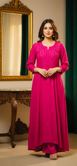 Woman in a pink traditional outfit standing in a room with a mirror and decorative items.