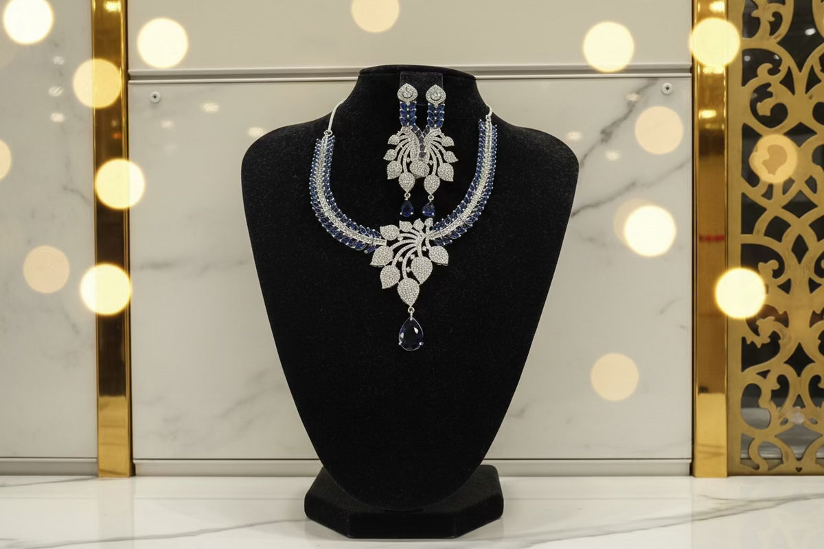 A necklace and earrings set featuring leaf elements, with blue sapphire stones and American diamonds. Party wear posh jewellery set.