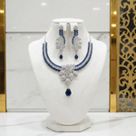 A necklace and earrings set featuring leaf elements, with blue sapphire stones and American diamonds. Party wear posh jewellery set.