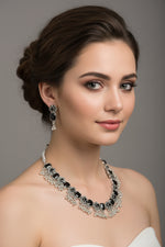 A oxidised black stone necklace with matching floral earrings, showcasing the tribal silver aesthetic.