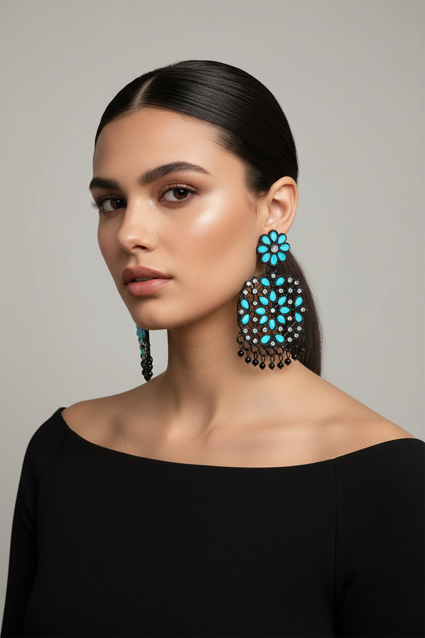 A pair of black earrings with sky blue stones coloured stone embellishments, displayed on an earring stand.