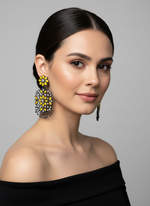 A pair of black earrings with yellow stones coloured stone embellishments, displayed on an earring stand.