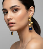 A pair of gold-plated earrings with navy blue Monalisa stone and coin details.